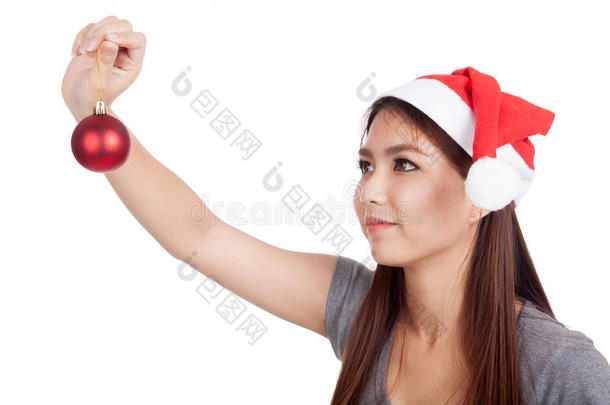 一个<strong>戴</strong>着圣诞帽的亚洲女孩看着手里的圣诞<strong>饰品</strong>