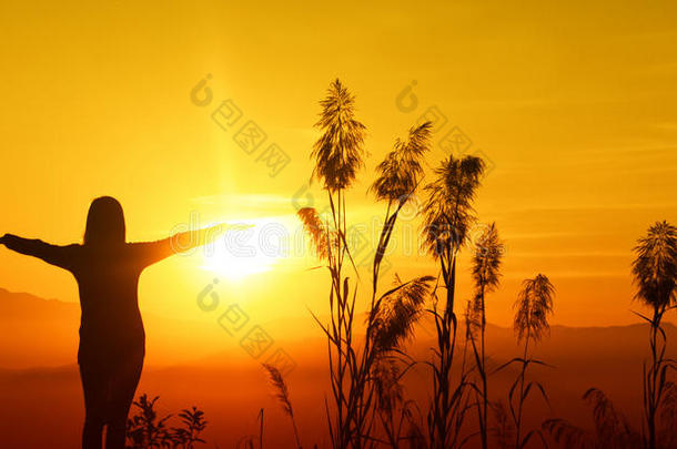 夕阳西下的剪影让年轻女人感受到自由和放松