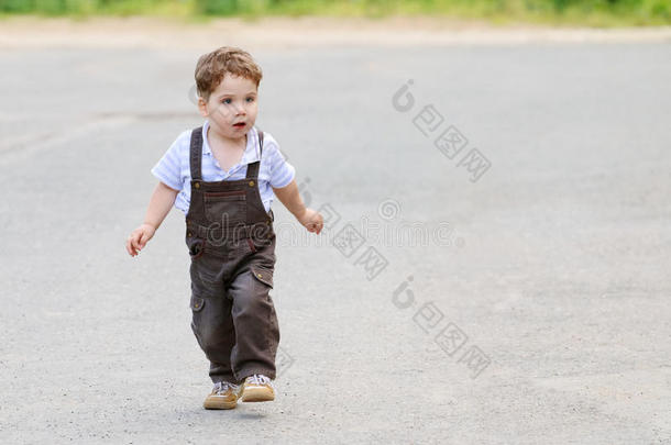 可爱漂亮的小男孩穿着棕色西装，走路