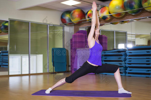 适合的女人在健身房的垫子上做瑜伽运动