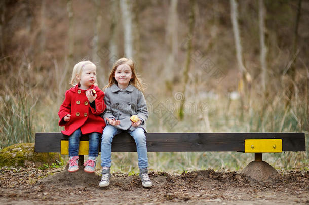 两个小妹妹坐在长凳上