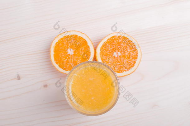 一杯新鲜的橙汁<strong>放</strong>在一张浅色的<strong>桌子上</strong>，<strong>上</strong>面<strong>放</strong>着橘子耳朵