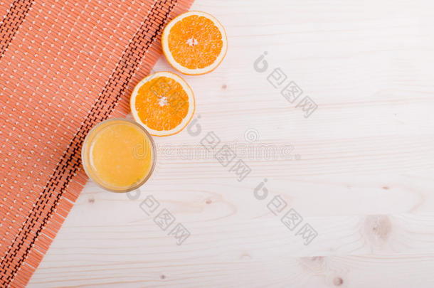 一杯新鲜的橙汁放在一张浅色的桌子上，上面放着橘子耳朵