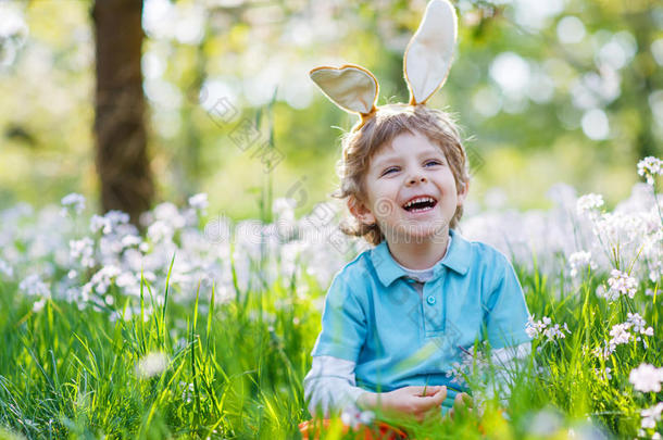 可爱快乐的小男孩戴着复活节兔子耳朵在春天绿色