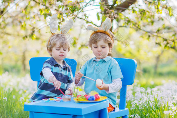 复活节兔子耳朵里的两个小朋友给鸡蛋着色