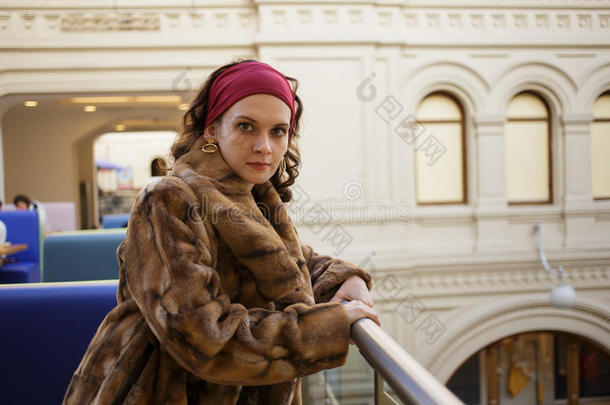 一个漂亮的女孩穿着豪华的冬季毛皮大衣在商店中心