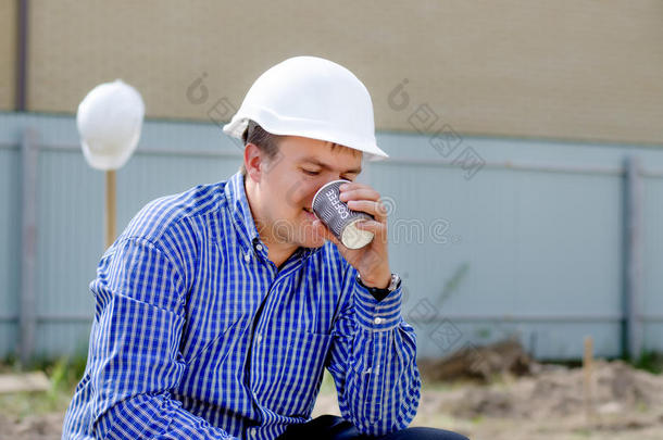 在建筑工地上喝咖啡的年轻工人