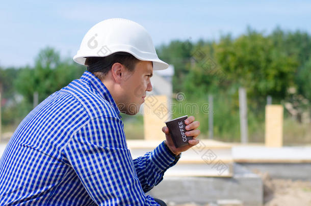 在建筑工地上喝咖啡的年轻工人