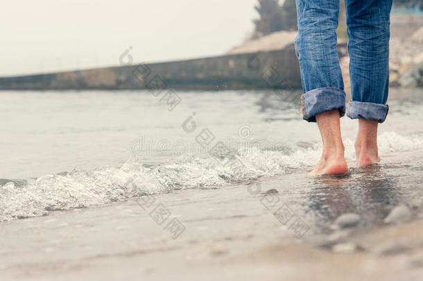 特写图片赤脚男子在海浪中的腿