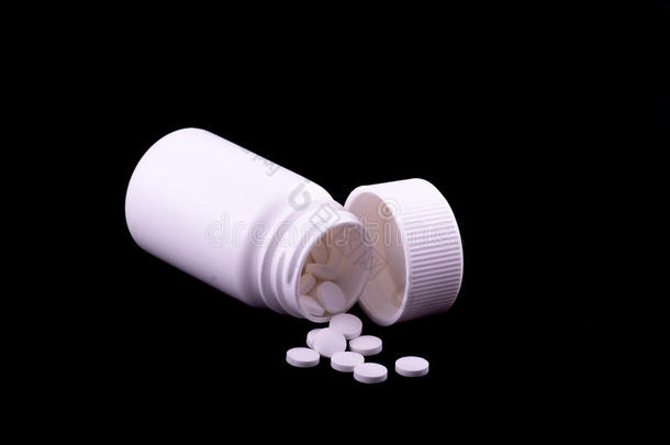 一个白色药瓶，黑色背景上有白色药丸