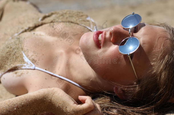 穿着比基尼的美女在沙滩上晒太阳