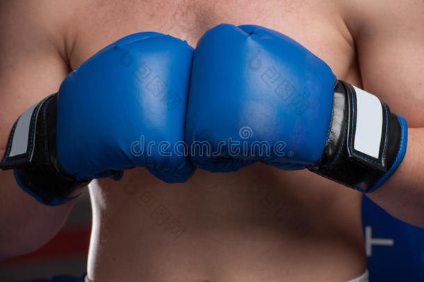 黑屋子里戴着蓝色手套的拳击手。