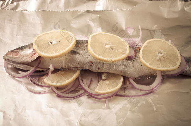 用柠檬和洋葱在锡纸上烤的鱼。染色的