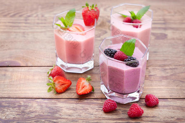 喝冰沙四个夏天草莓，黑莓，猕猴桃，覆盆子在木制桌子上。