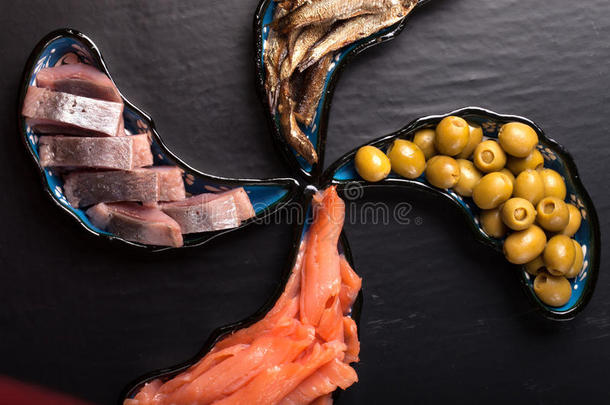 黑底魔术盘子上的鱼肉和橄榄