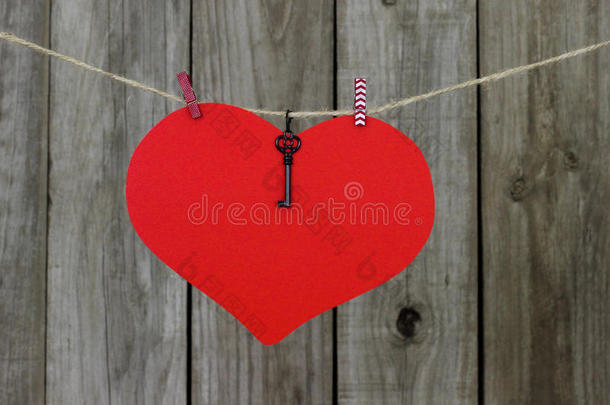 <strong>大</strong>红色心形标志，钥匙挂在晾衣绳上，靠着古老的风化木栅栏