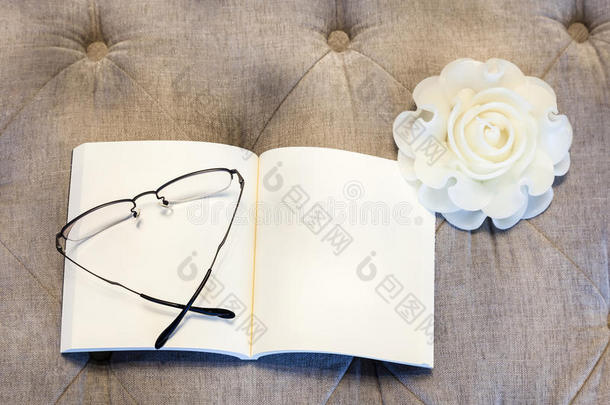 带<strong>眼镜</strong>的沙发上放着玫瑰蜡烛的空白书