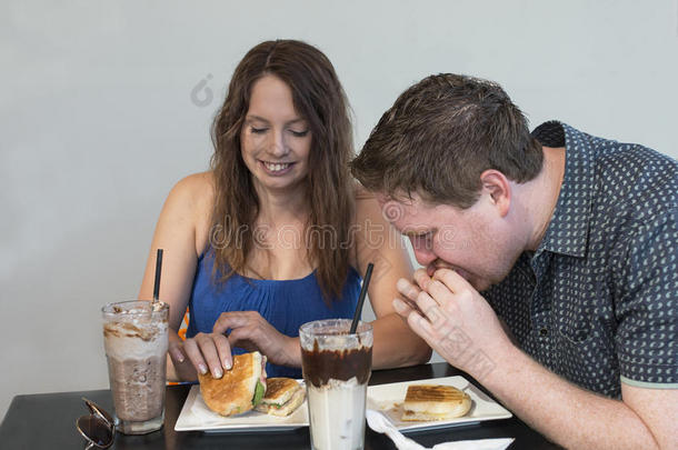一个年轻的女人和一个男人在吃着一个香肠。