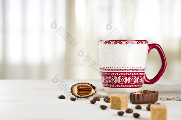 桌上的热咖啡杯在模糊的窗帘背景上
