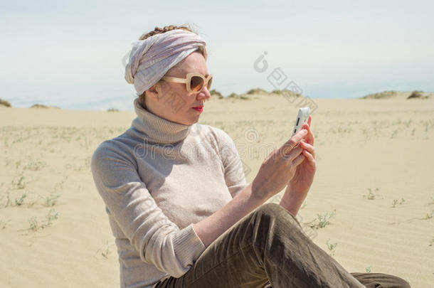 一个女人在<strong>沙漠里</strong>看着智能手机
