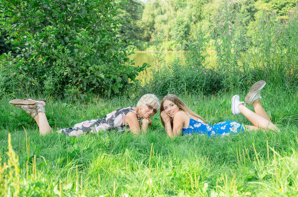 两个不同年代的女人躺在草地上。母女俩。外婆外孙女外婆外孙