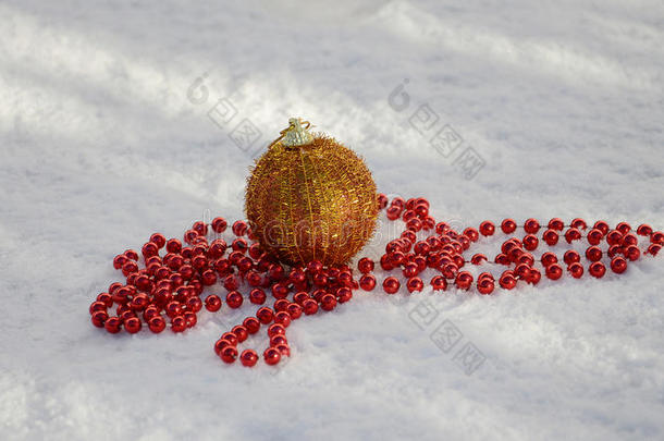 金色的圣诞宝和红色的珍珠在雪地上