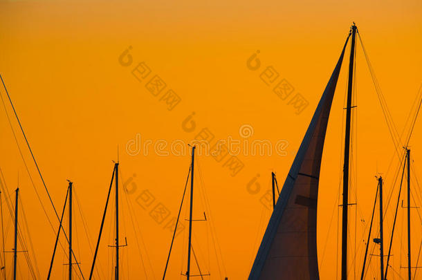 黄昏时，在橙色的天空下，关闭一个帆的轮廓
