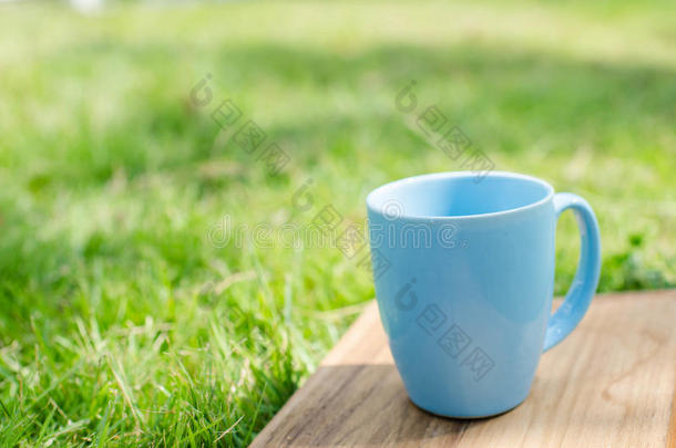 绿色草木木板上的蓝色杯子