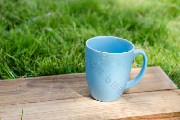 绿色草木木板上的蓝色杯子