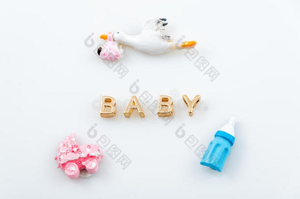 金色的字母。 字宝宝在白色与小玩具。 奶嘴，婴儿车和抱着新生儿的鸟。