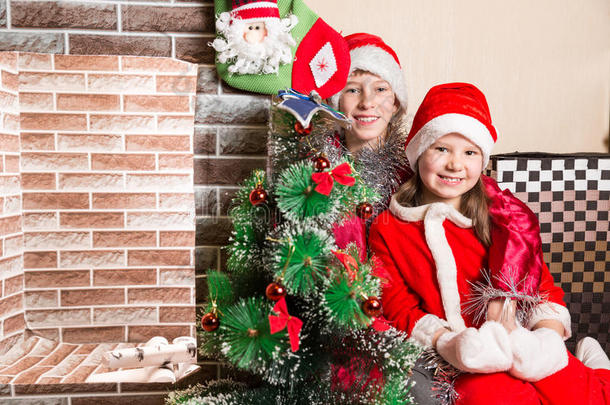 哥哥和姐姐穿着圣诞老人的服装在壁炉旁。 圣诞节