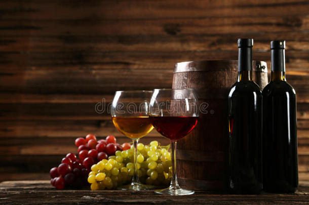 一杯红白葡萄酒，背景是棕色的木制背景上的葡萄