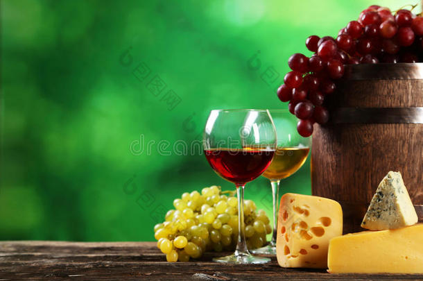 棕色木制背景上的一杯红白酒、奶酪和葡萄