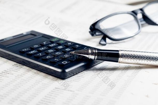 商务钢笔、计算器和金融图表上的眼镜