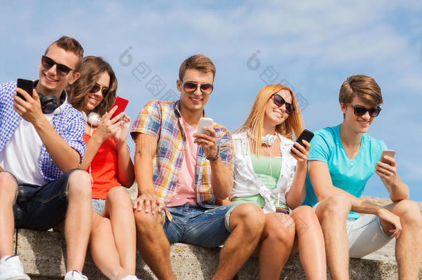 一群带着智能手机在户外微笑的朋友