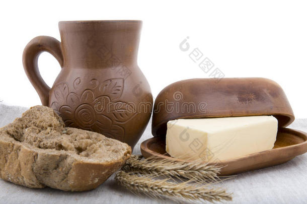 新鲜牛奶，黄油和黑麦面包，亚麻桌布上的实物陶器