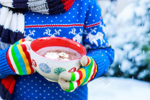 孩子的手拿着雪花和热可可的大杯子