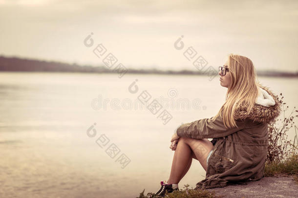 傍晚日落时，女孩坐在湖边