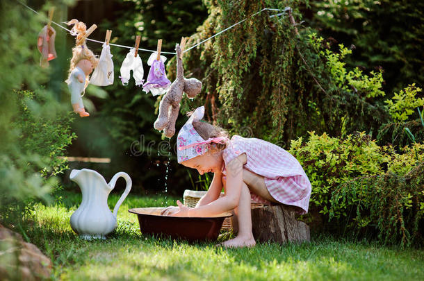可爱微笑的女孩在阳光明媚的夏天花园里玩玩具洗