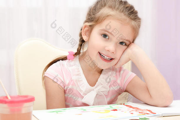 可爱的微笑小女孩用颜料和画笔画画