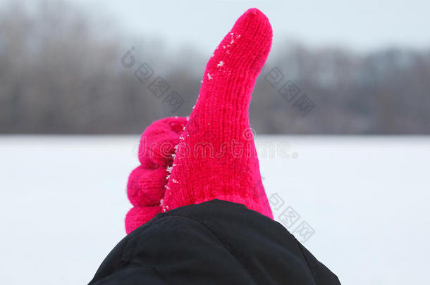 手在红色羊毛手套上，拇指在冬天的背景上
