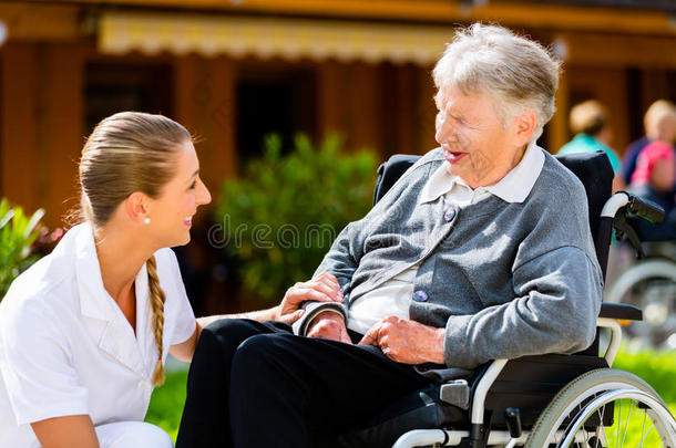 护士推着轮椅上的老年妇女步行