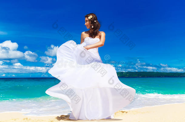 美丽的黑发新娘穿着白色婚纱，白色的大火车和婚礼花束站在海边