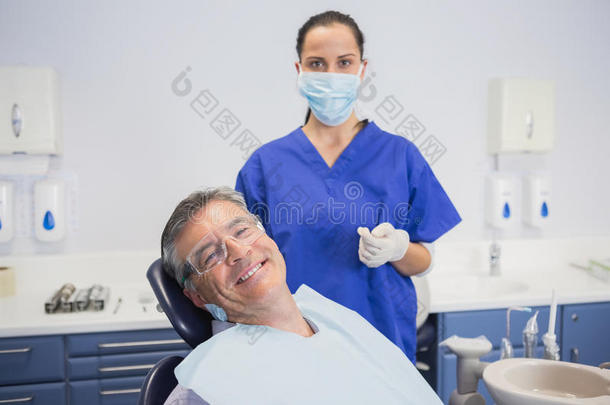 牙医戴着外科口罩，带着微笑的病人