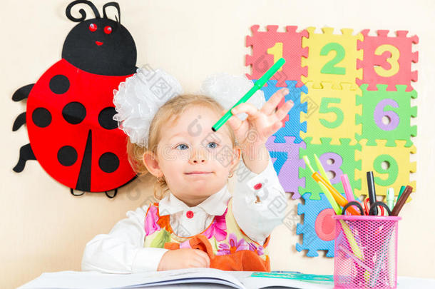 可爱的小女孩在幼儿园的桌子上用彩色铅笔和毛毡笔画画