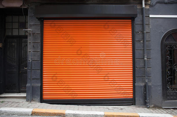 封闭的商店外部覆盖着橙色的金属门