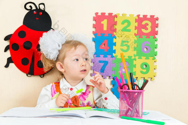 可爱的女孩在幼儿园的桌子上用彩色铅笔画画