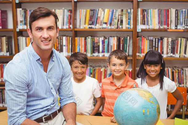 可爱的学生和老师在图书馆看地球仪