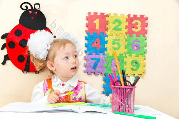 可爱的女孩在幼儿园的桌子上用<strong>彩色铅笔画</strong>画