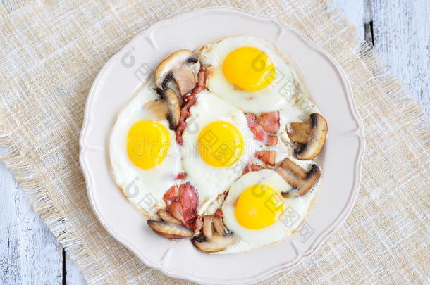 早餐煎鸡蛋，在木桌上放培根和蘑菇